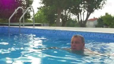 在阳光明媚的夏日里，老年人在户外游泳池里游泳，在<strong>水中</strong>放松